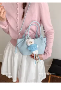 Detailansicht einer stilvollen hellblauen Cloud-Tasche an einem Modell in rosa Strickjacke.
