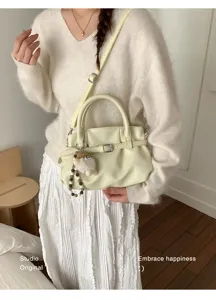 Nahaufnahme einer hellgelben Vintage-Handtasche mit Falten und einem süßen Plüschtier-Detail
