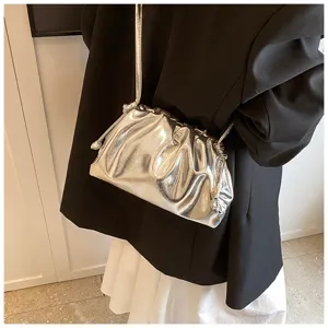 Detail van een zilveren geplooide wolkentas met metallic afwerking over de schouder