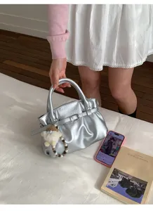 Silberne Falten-Handtasche mit modischem Gürteldetail in einer wohnlichen Atmosphäre