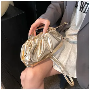 Detailweergave van de goudkleurige metallic finish en plooien van deze elegante cloud bag