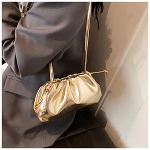 Elegante gouden metallic geplooide cloud schoudertas over de schouder gedragen. Detail.