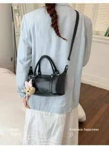 Vue détaillée d'un sac Boston élégant en cuir souple noir avec un ours en peluche