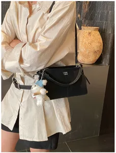 Detailed view of a black soft-side commuter tote bag featuring a cute white plush bear charm.