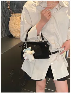 Black soft tote bag with cute plush bear charm worn by model in casual style