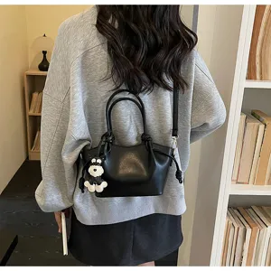 Detailansicht einer stilvollen schwarzen Leder-Eimertasche mit einem Schnauzer-Anhänger.