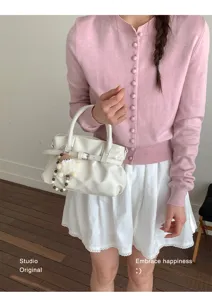 Detail einer weißen Vintage-Handtasche mit Falten und modischem Lederschnallenriemen.