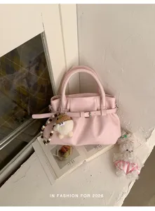 Detailansicht der rosa Faltenhandtasche mit Gürteldesign und süßem Puppenanhänger