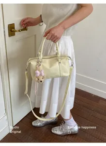Détail d'un sac Boston en cuir souple crème avec un charmant porte-clés ours