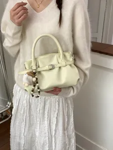 Elegante cremefarbene Faltenhandtasche mit Vintage-Gürtelschnalle und Plüsch-Anhänger