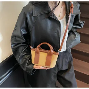 Primo piano di una piccola borsa a secchiello in tela a contrasto con finiture in pelle