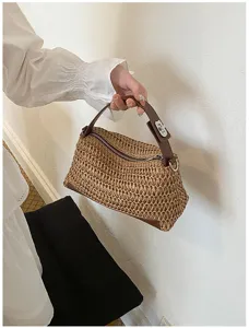 Vue détaillée d'un sac polochon en paille tressée à la main avec une bandoulière marron.