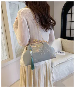 Elegante borsa da sera azzurra con ricamo dorato e nappa verde, vista posteriore.