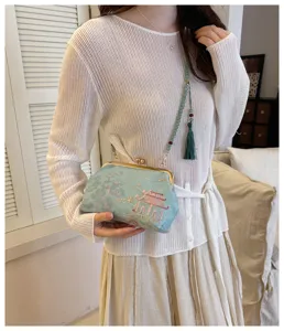 Dettaglio della pochette ricamata azzurro chiaro con tracolla di perline e nappa