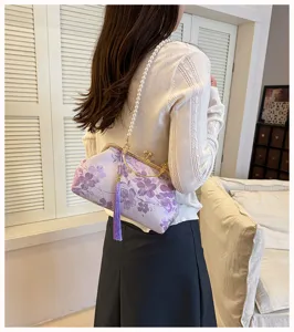 Elegante lila Abendtasche mit Blumenstickerei und Perlenriemen an der Damen Schulter.