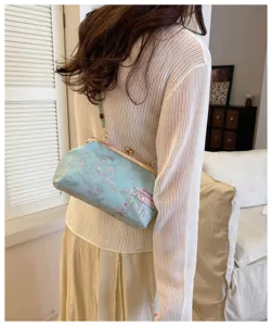 Dettaglio di un'elegante pochette ricamata azzurra con una classica chiusura in metallo.