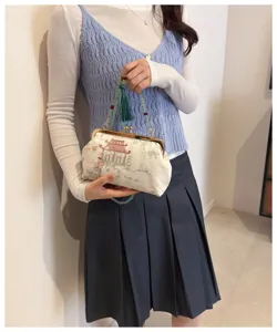 Dettaglio di un'elegante pochette ricamata con cinturino di perline e nappa verde.