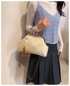 Elegante borsa da sera ricamata con nappine mostrata da una modella come borsa a tracolla