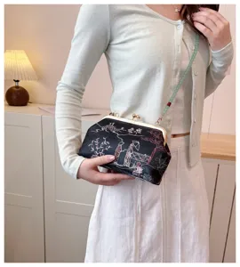 Clutch da festa ricamata nera con tracolla in rilievo verde su una modella