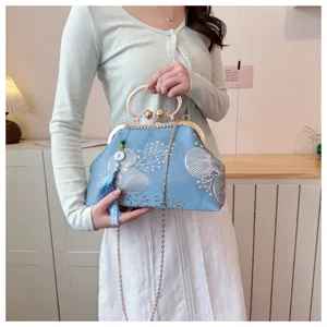 Dettaglio di un'elegante borsa da sera ricamata blu con nappina e chiusura in strass.