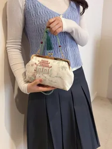 Elegante borsa ricamata con manico in perle verdi e nappina indossata da una modella