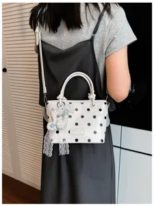 Elegante weiße Beuteltasche mit schwarzen Punkten und einem schicken Spitzenanhänger