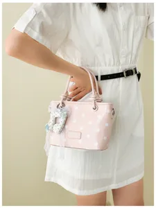 Detailansicht einer stilvollen rosa gepunkteten Handtasche mit Musiknoten-Anhänger.