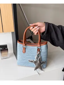 Vue détaillée d'un sac seau en denim bleu de style coréen avec des poignées brunes et une étoile