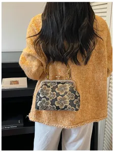 Detailed back view of a woman carrying an embroidered floral shell bag with chain strap