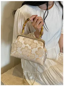 Detailed close-up of a floral embroidered clasp bag with a vintage bamboo handle.
