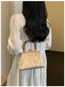 Elegant embroidered floral evening bag with bamboo handle shown as a detail view