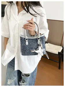 Gros plan d'un sac seau en denim bleu avec poignées argentées et pendentif en étoile