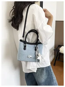 Détail du sac seau en denim bleu clair avec breloque étoile et bandoulière noire