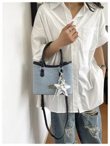 Sac seau décontracté en jean bleu clair avec pendentif étoile porté par un modèle