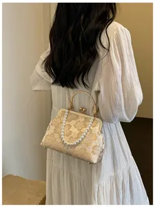 Elegant floral embroidered shell evening bag with gold clasp and pearl strap detail view