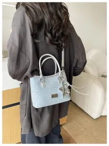 Sac seau en denim bleu clair avec poignée argentée et détail de pendentif étoile.