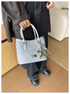 Détail du sac cabas en denim bleu clair avec anses argentées et breloque étoile