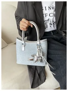 Détail d'un sac à main en denim bleu clair avec breloque étoile argentée