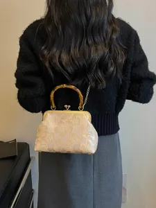 Beige embroidered floral kiss-lock evening bag with bamboo handle worn by model