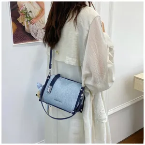 Light blue denim bucket bag shown as a crossbody shoulder bag in a lifestyle setting.