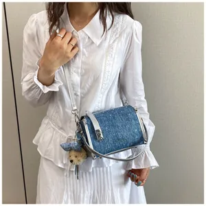 Close-up detail view of denim blue crossbody bag styled with a white ruffled outfit
