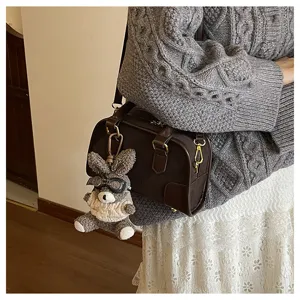 Detailed view of dark brown soft leather pillow bag with cute plush rabbit charm