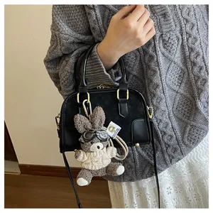 Close-up of a stylish black mini pillow handbag featuring a cute plush bunny keychain