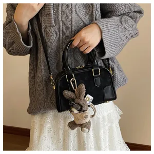 Detailed shot of stylish black minimalist pillow bag with cute plush keychain charm