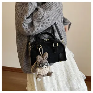 Detailed shot of the black soft leather pillow bag featuring a cute bunny charm pendant.