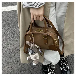 Stylish brown handbag with cute teddy bear charm shown in a street lifestyle shot