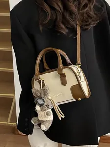 Stylish cream and brown bowling handbag with a cute rabbit charm on a black blazer