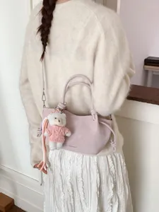 Elegante rosa plissierte Beuteltasche mit Bärenanhänger, am Modell für Größe und Stil