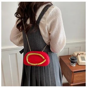 Stylish red ruched evening clutch bag featuring a gold sculptural metal handle and chain