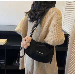 Sac à bandoulière noir givré vintage avec breloque ours porté sur le dos du modèle
